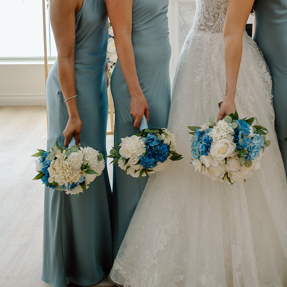 Elegant classic blue and white wedding bouquet held by bride with bridesmaids holding bridesmaid bouquets