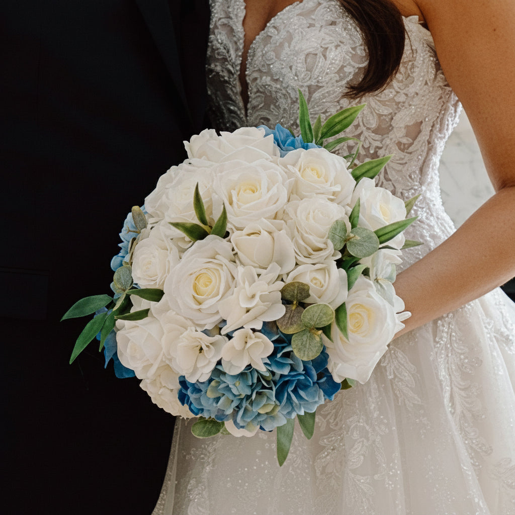 Bouquet of white and blue flowers held by a bride in a wedding dress.