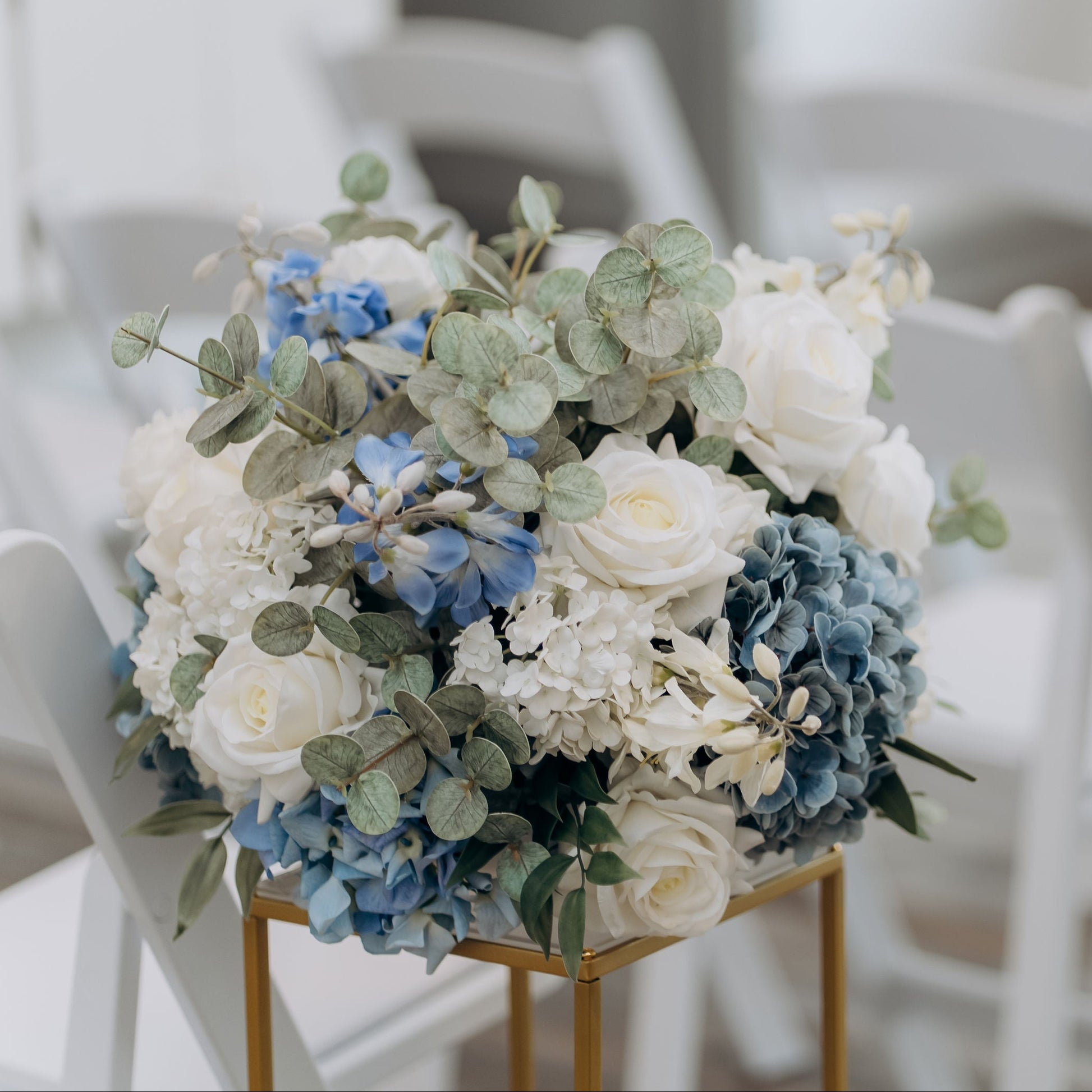 Decorative floral arrangements on stands in a wedding setup with white chairs.