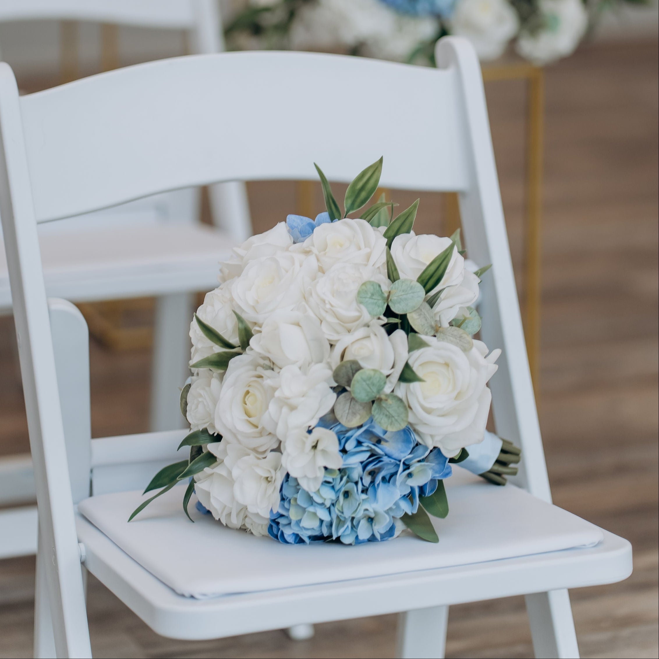 White chair with a bouquet of white and blue flowers in an indoor setting.